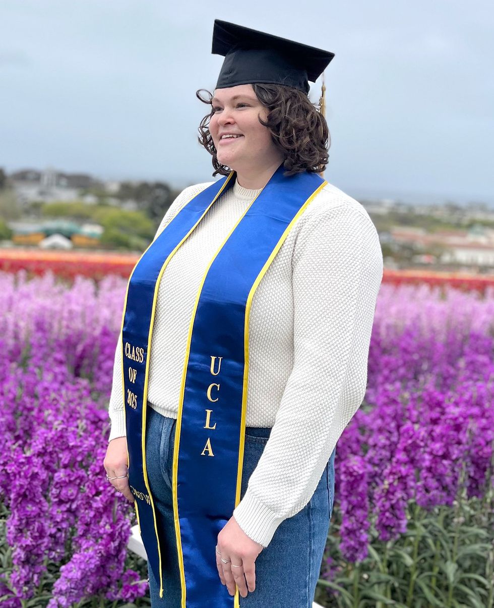 2025 Point Foundation Scholar Graduate Kelsey graduation cap and sash in lavender field
