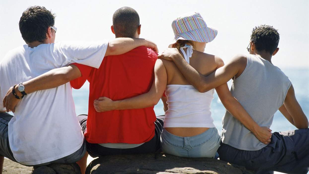A back view of four people with their arms around each other.