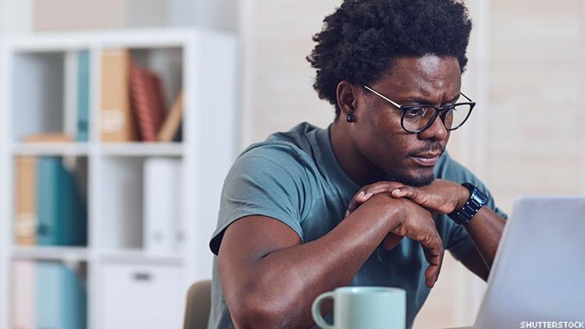 A Black man sitting at a laptop.