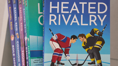 A close-up of the illustrated cover of Heated Rivalry by Rachel Reid