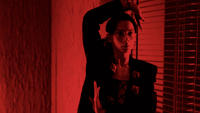 A dancer striking a voguing pose under red lighting