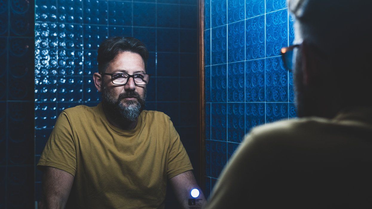 A depressed man looking into a mirror