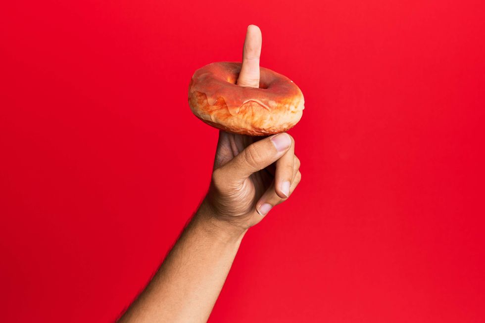 A finger poking through the hole of a donut