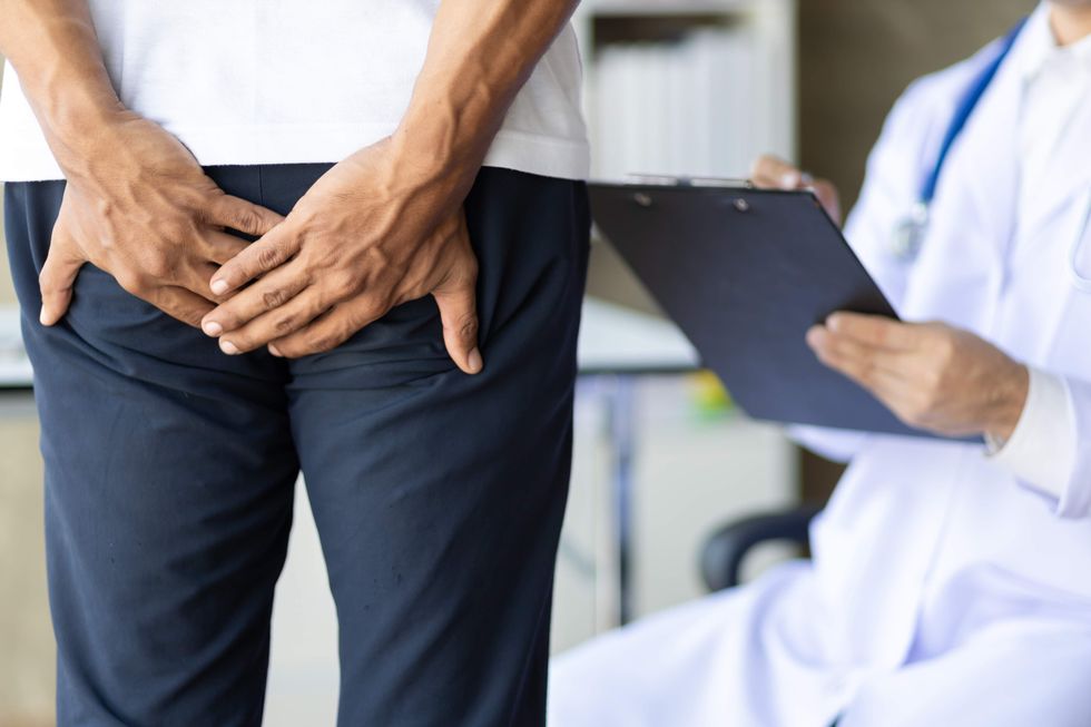 A man holding his butt while standing in front of a doctor