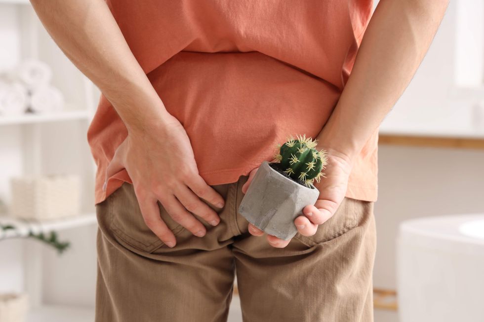 A man holding his putt and a small potted cactus