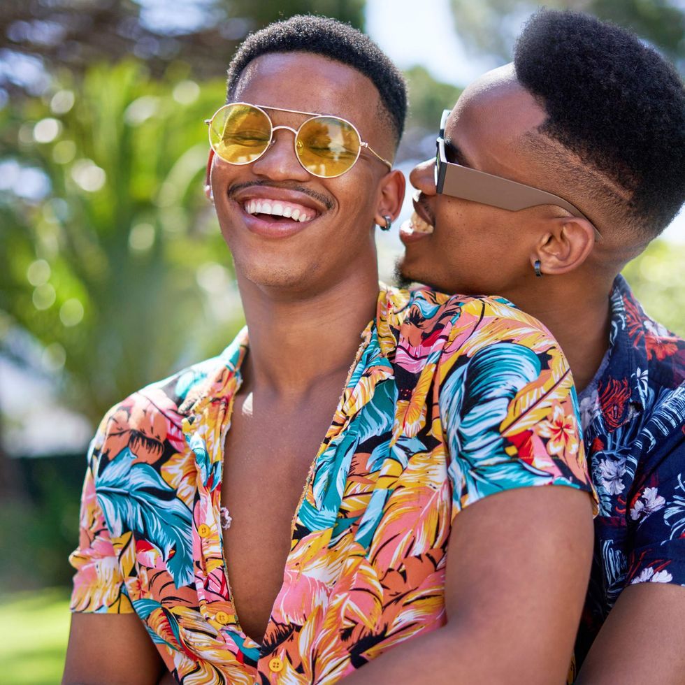 A man holding hugging another man from behind while they laugh
