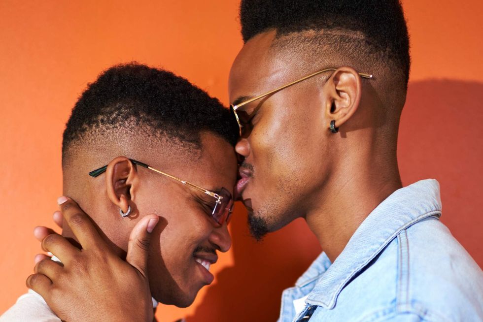 A man kissing another man on the forehead