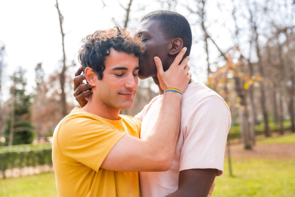 A man kissing another man's head