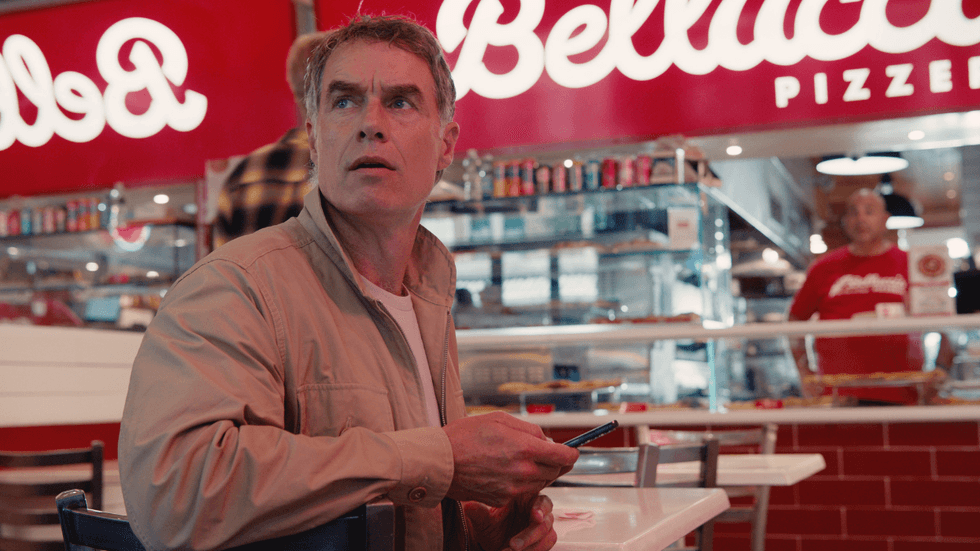 A man sitting at a table in a pizza shop