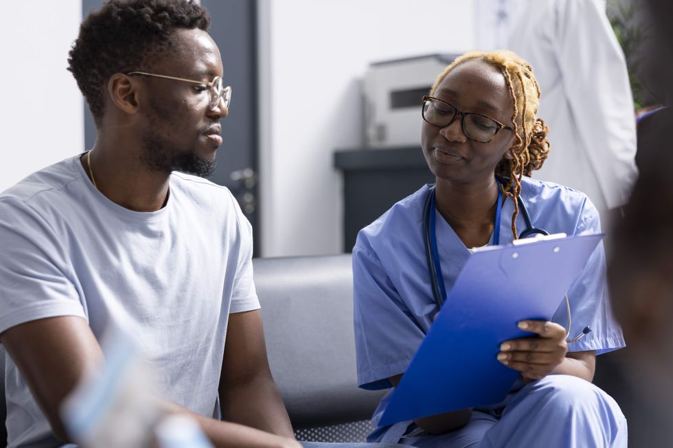 A man sitting with a nurse holding a clipboard