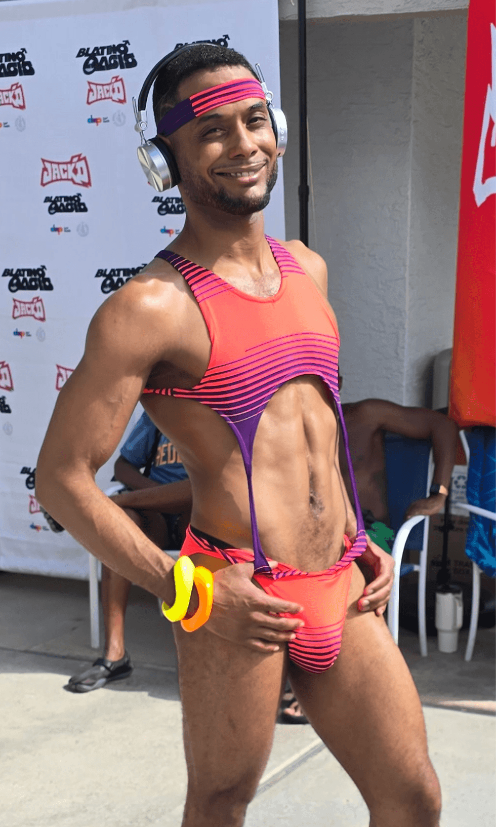 A model wearing a neon pink and purple cutout bodysuit, headphones, and matching accessories poses during NoRal Apparel\u2019s fashion showcase at SunLit Men of Color Retreat in Palm Springs