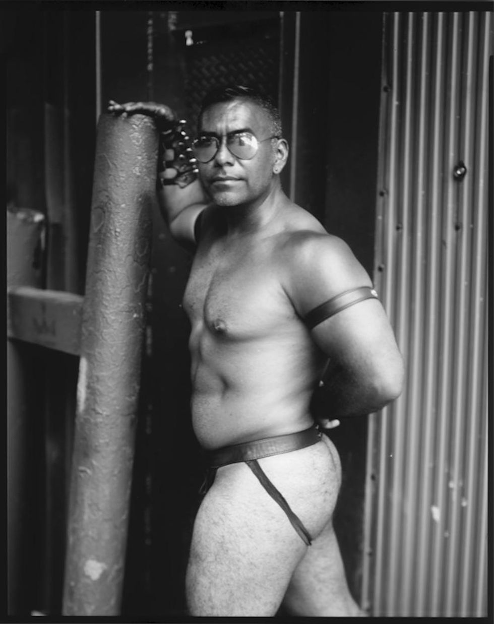 A muscular man in aviator shades and a leather jockstrap, posiing.