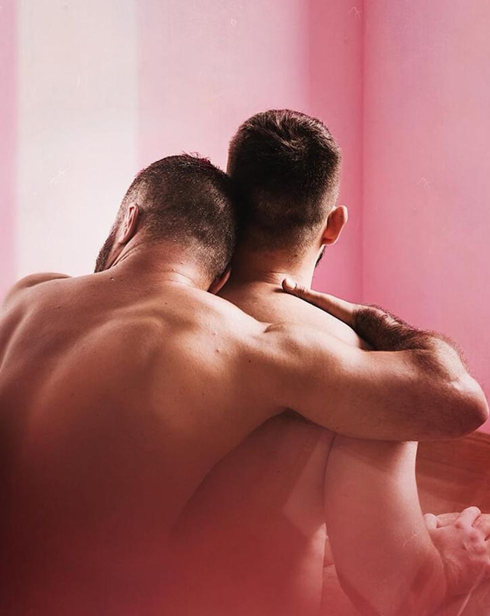 A photo of two muscular men hugging from behind.