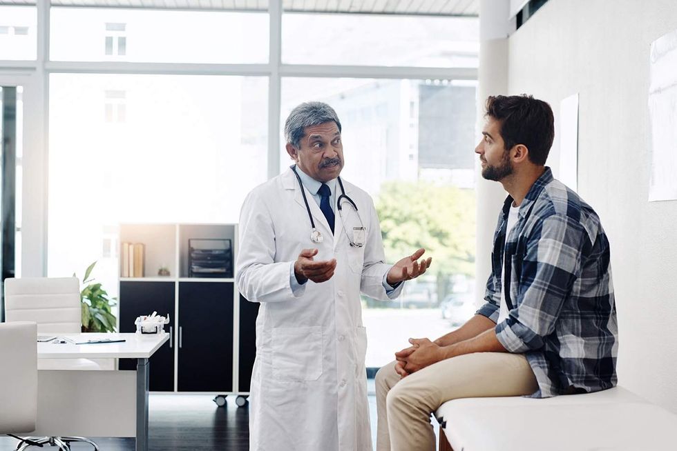 A physican talking to a man in a doctor's office.