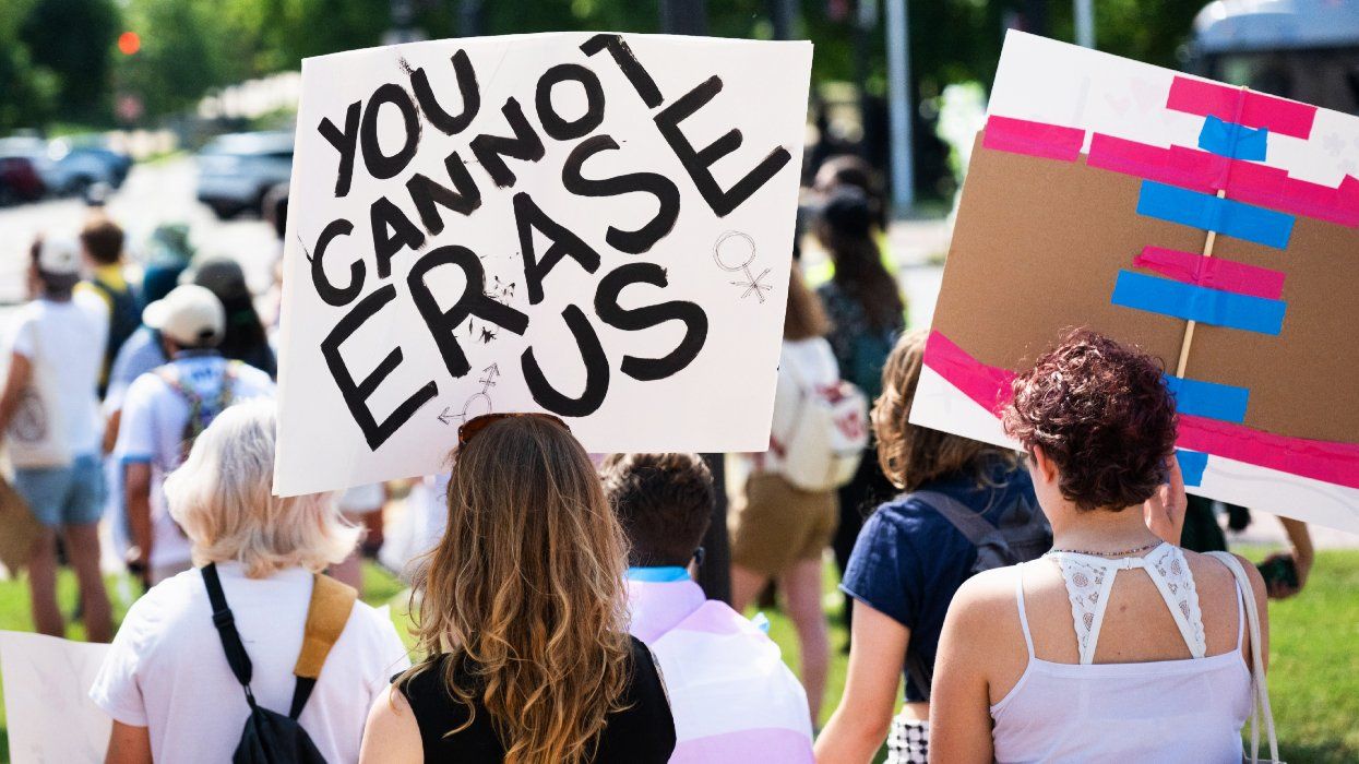 A protester holds a sign that reads you cannot erase us