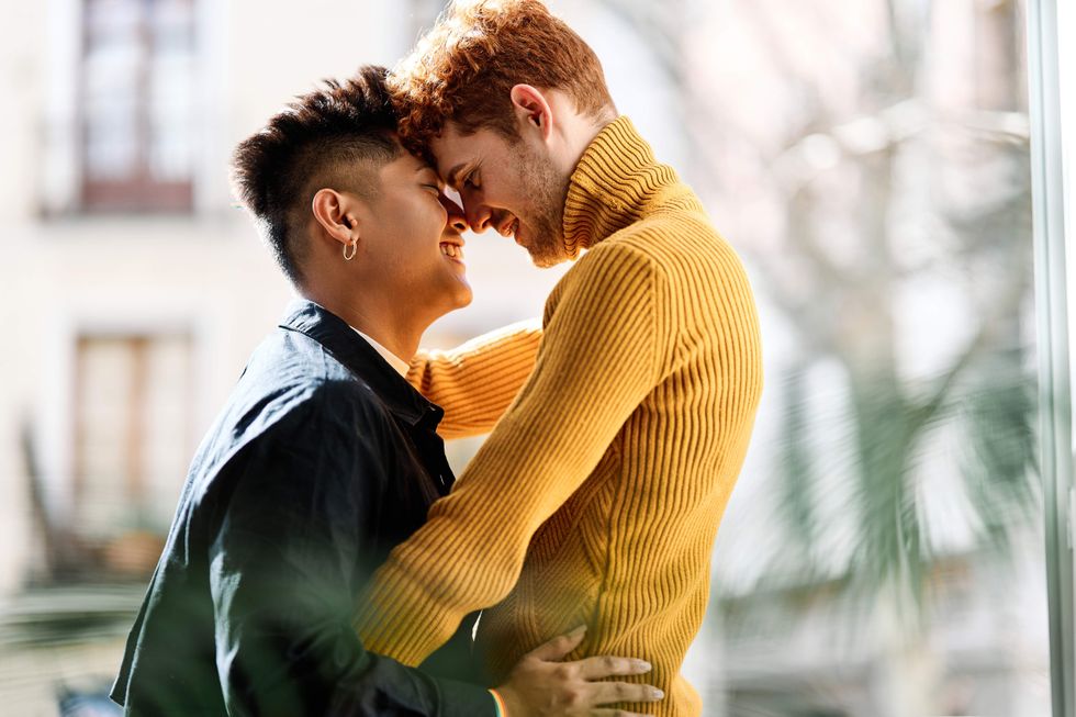 A queer couple holding each other and pressing their foreheads together