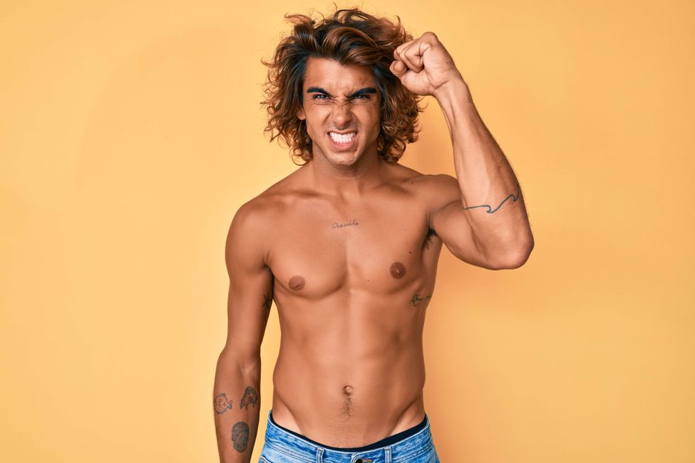 A shirtless man with his fist in the air