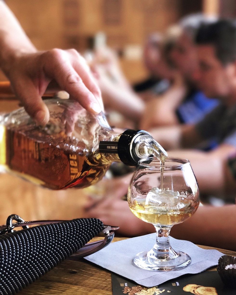 A shot of bourbon is being poured into a glass.
