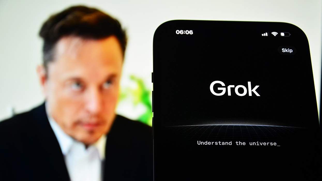 A smartphone screen promotes the chatbot Grok while Elon Musk is in soft focus in the background