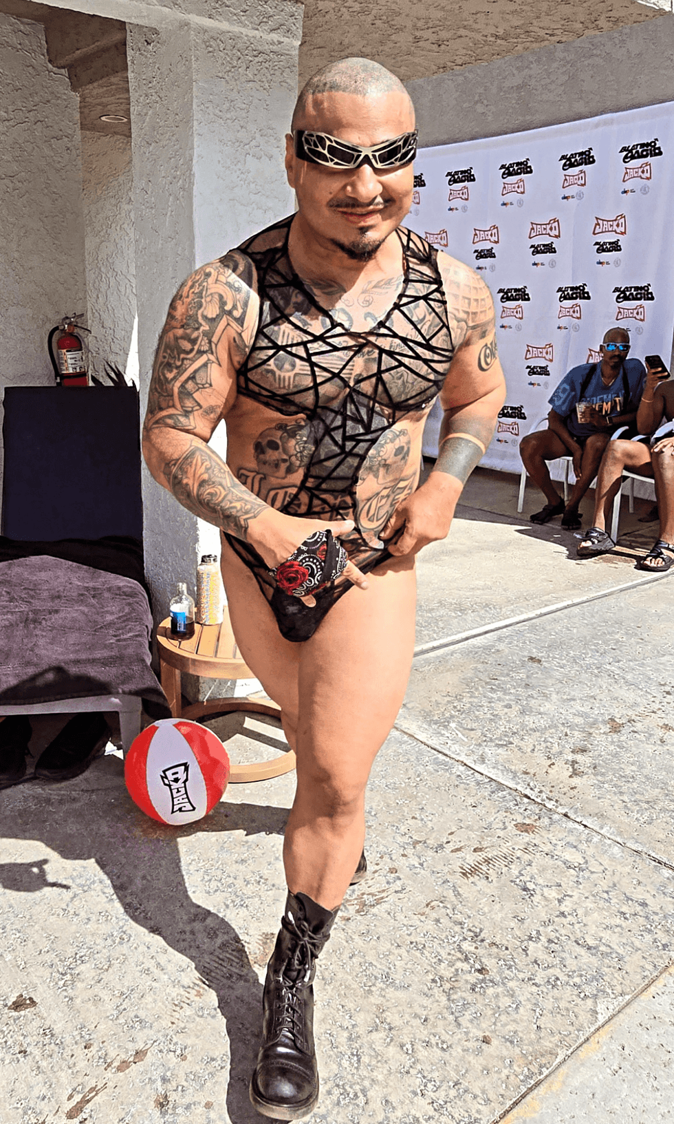 A tattooed model wearing black mesh-inspired swimwear and boots walks during NoRal Apparel\u2019s fashion showcase at SunLit Men of Color Retreat in Palm Springs