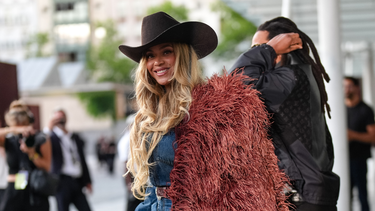 A woman in a denim outfit with a reddish-brown fur coat and brown cowboy hat