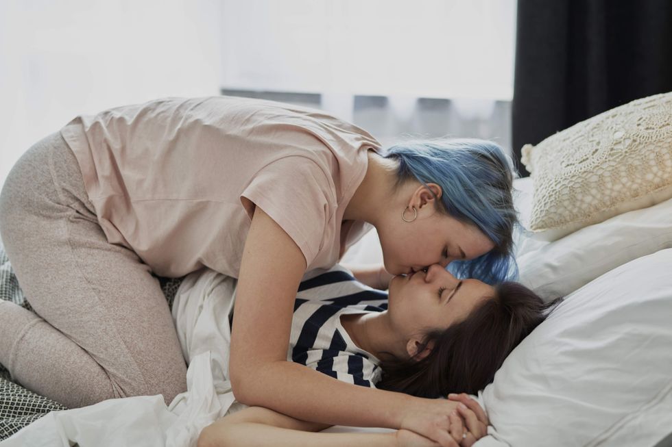 A woman lying on top of another woman and kissing her