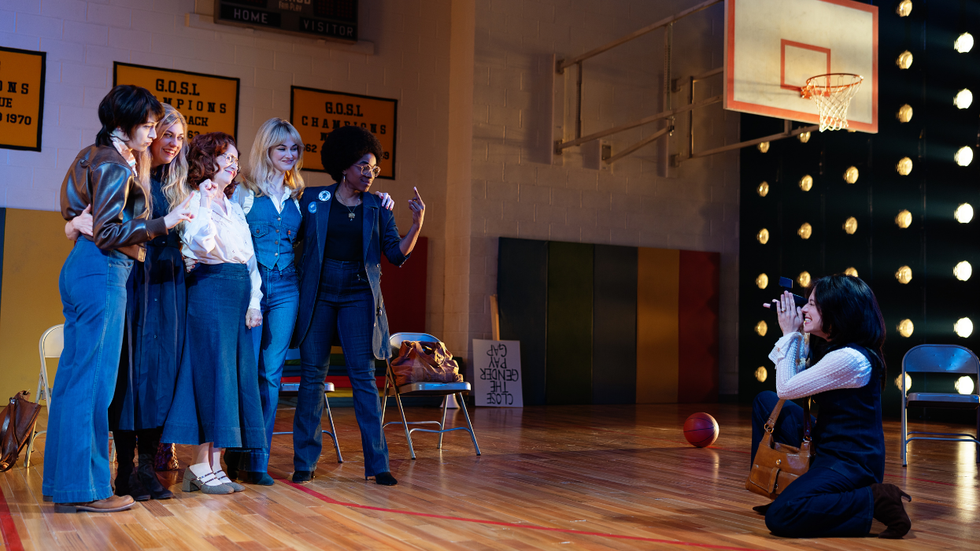A woman on her knees taking a photo of a group of women