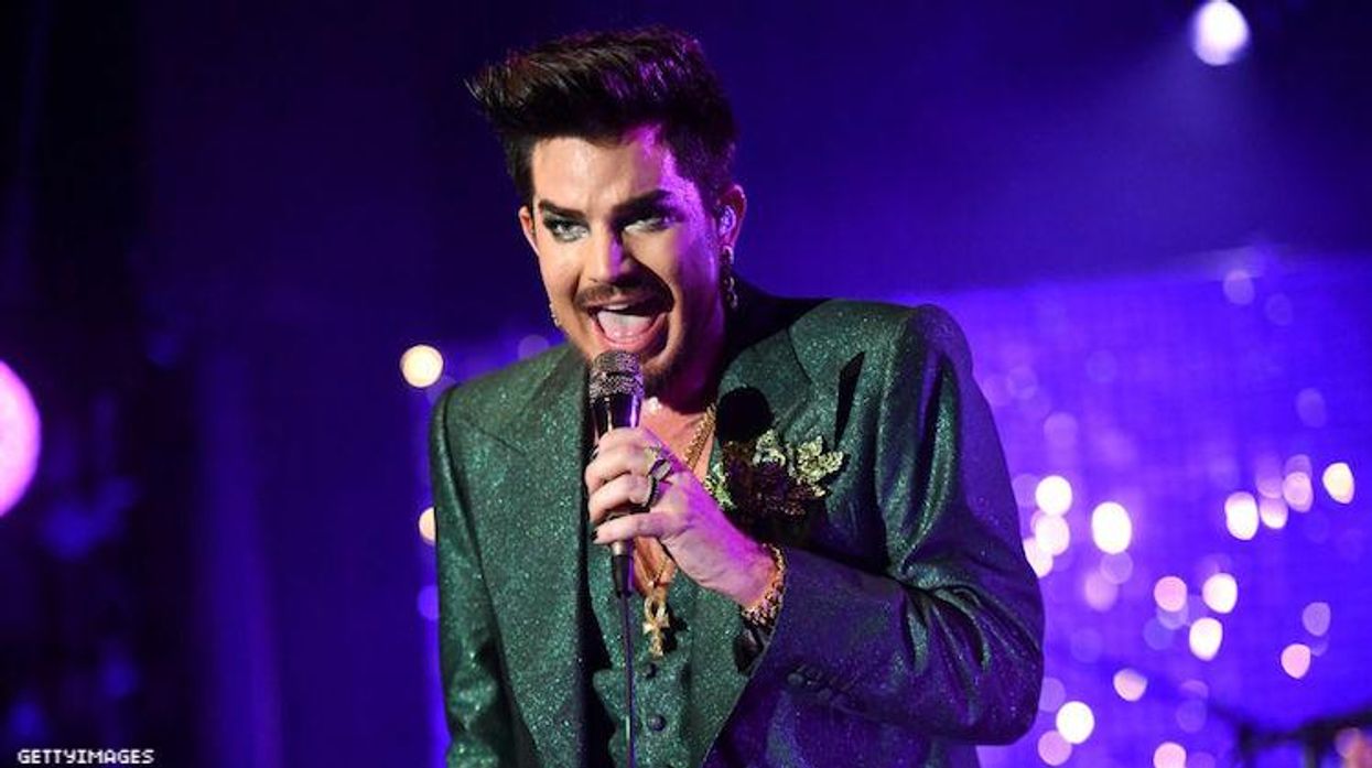 Adam Lambert performing in a green suit.