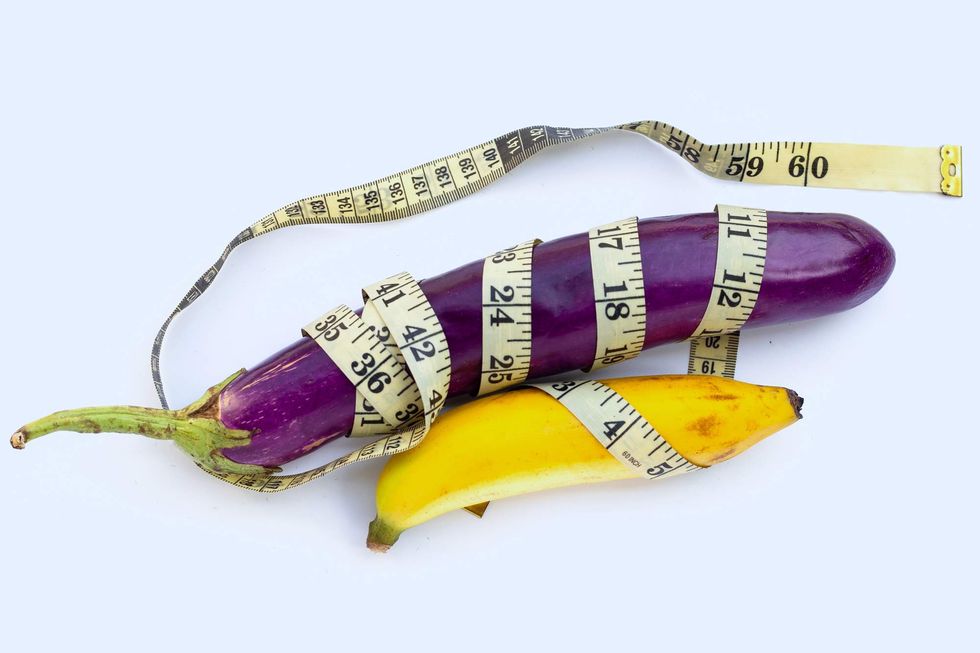 An eggplant and banana wrapped in a measuring tape