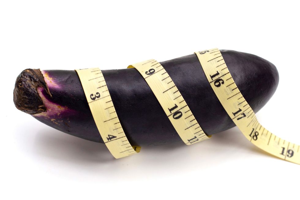 An eggplant with a measuring tape wrapped around it.