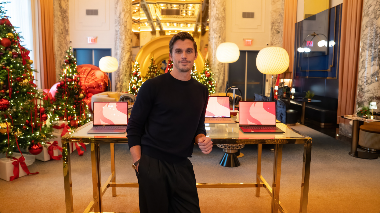 Antoni Porowski leaning up against a table with laptops