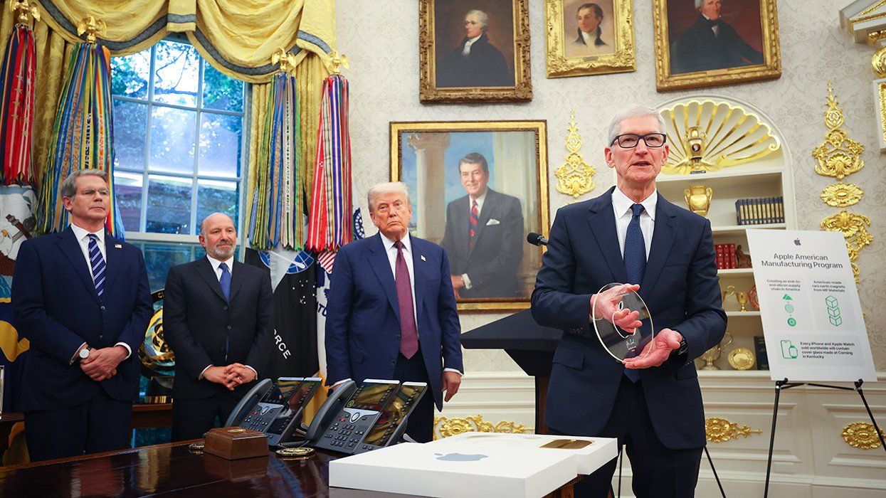 Apple CEO Tim Cook displays an engraved glass disc presented to US President Donald Trump during an event in the Oval Office