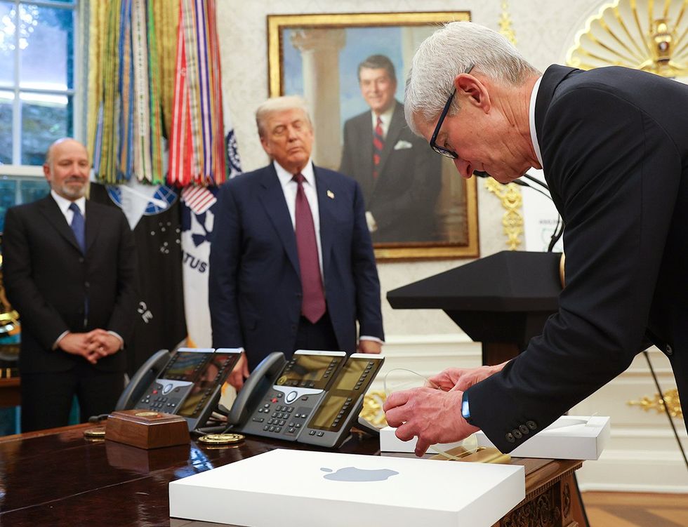 Apple CEO Tim Cook displays an engraved glass disc presented to US President Donald Trump during an event in the Oval Office