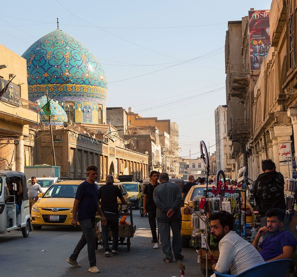 Baghdad Iraq Haydar Khana Mosque with a blue dome and people at the market in al Mutanabbi street
