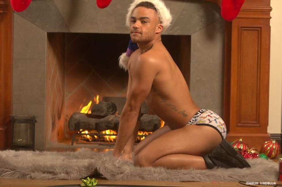 Beaux Banks wearing underwear and a Christmas hat, kneeling on a carpet.