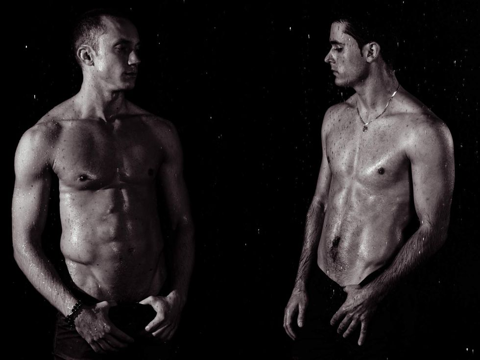 Black and white image of two shirtless men looking at each other