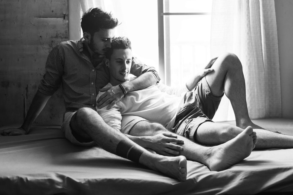 Black and white photo or two men laying against each other