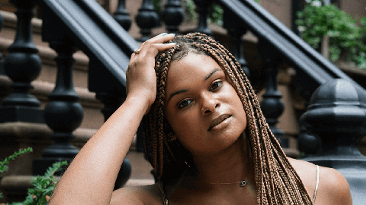 Black trans woman Raquel Willis sitting on a stoop