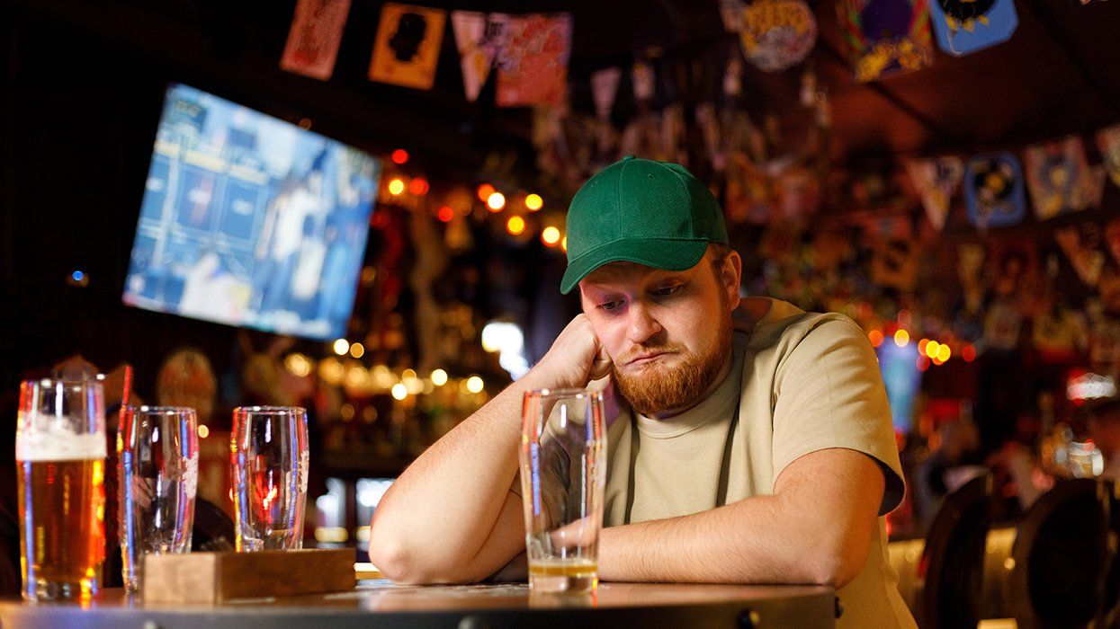 bored man alone in a bar with multiple beer glasses