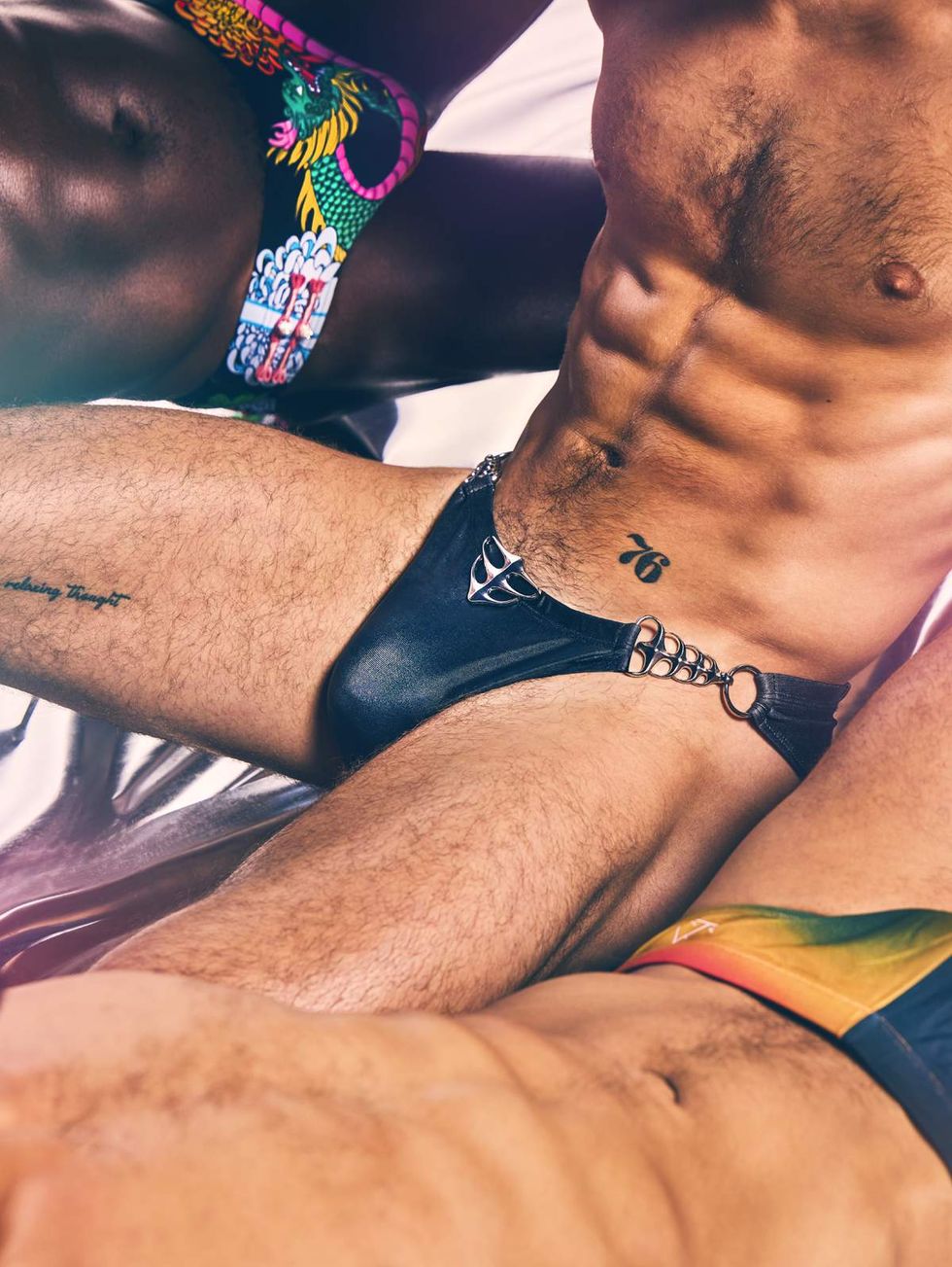 Close up of Chris Patterson-Rosso, Aydin Eyikan, and Hector Juan Maisonet modeling swimwear