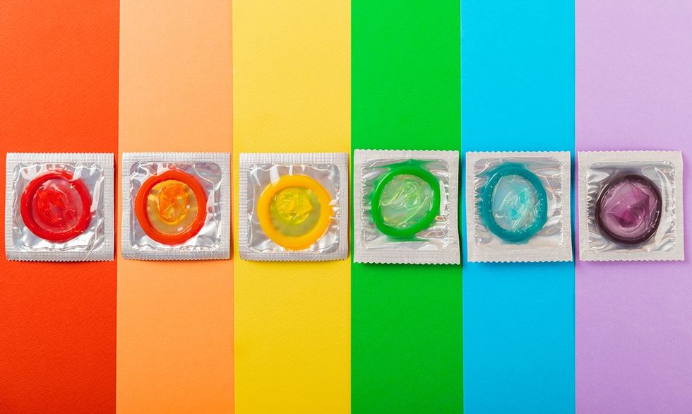 condoms in wrappers multiple colors lined up on rainbow paper background