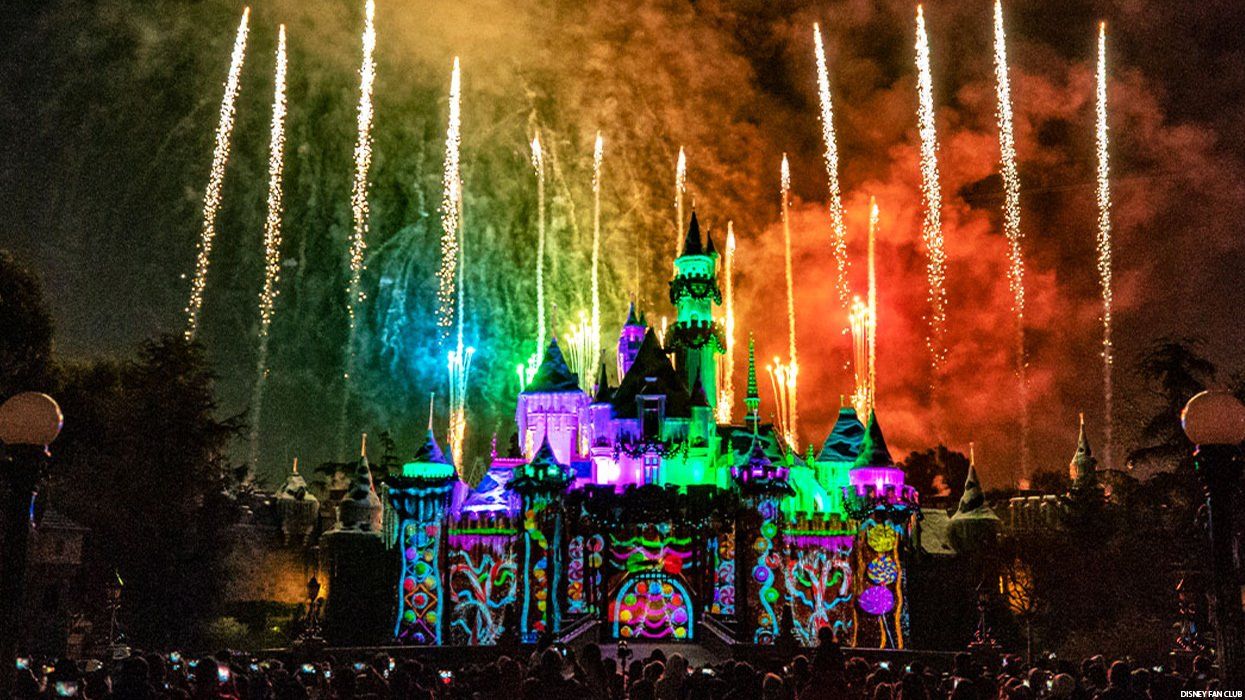 disney castle lit up by rainbows
