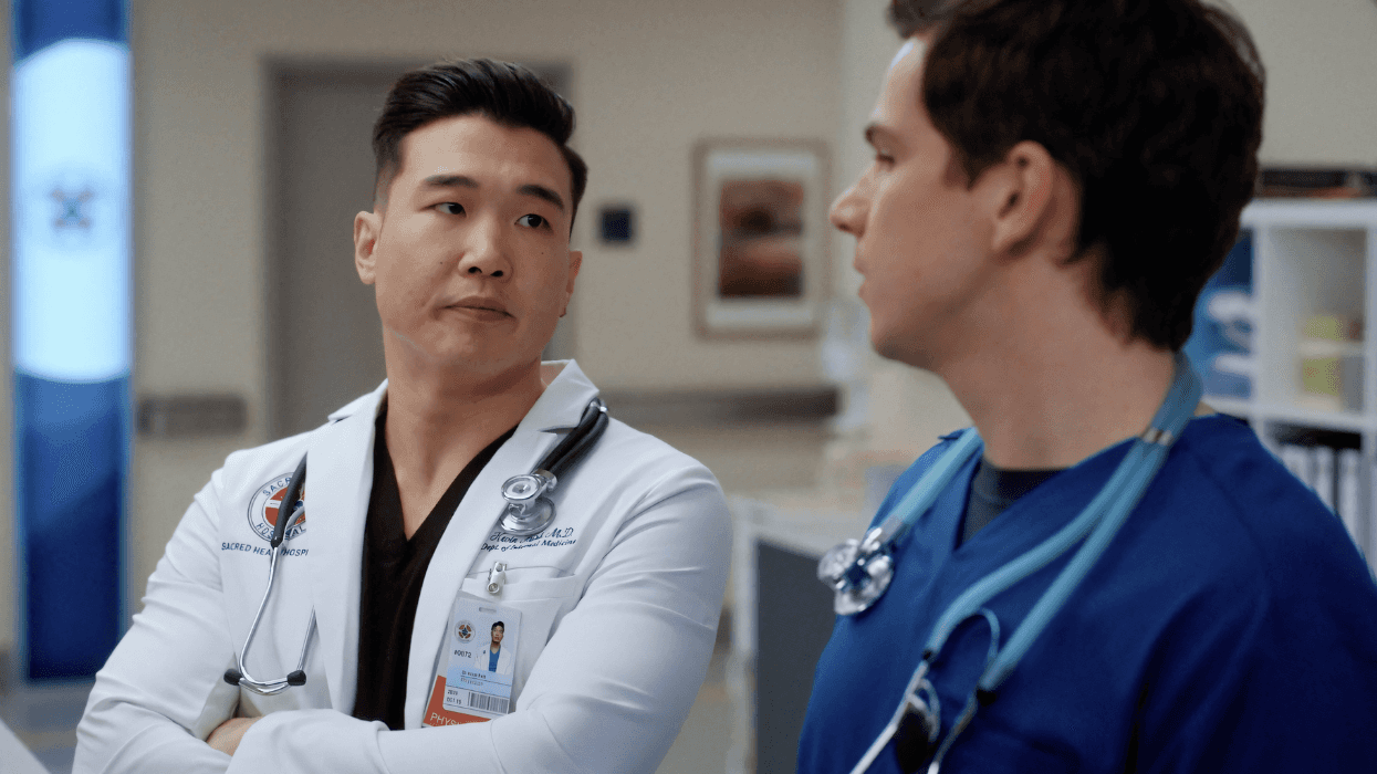 Dr. Park and Dr. Asher Green stand side by side in a hospital corridor, talking in a scene from Scrubs.