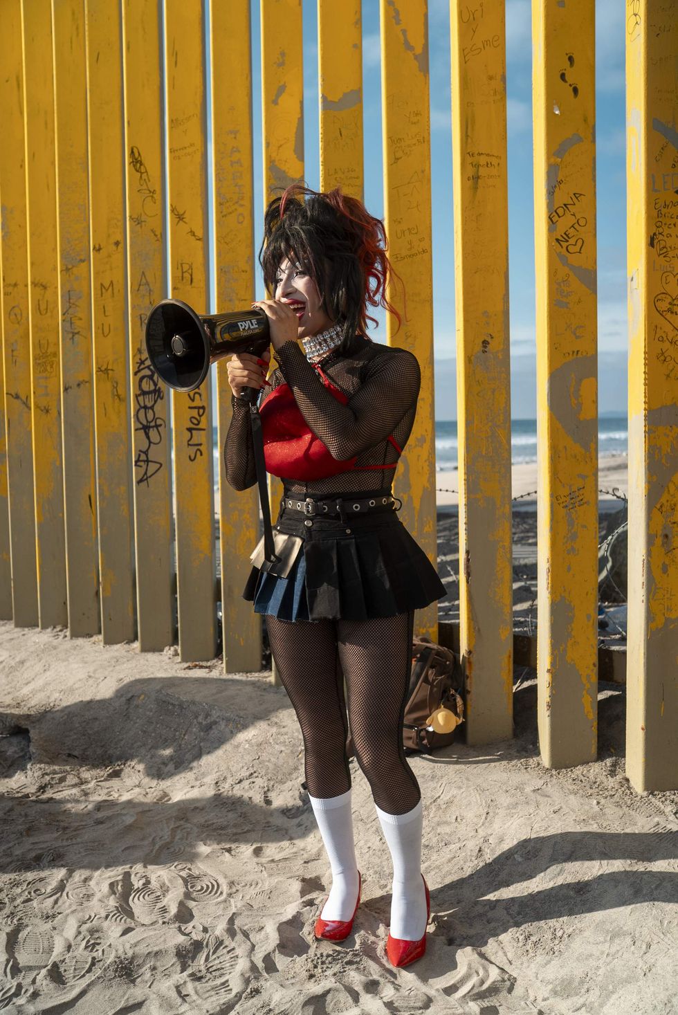 Drag queen speaks with megaphone in front of U.S.-Mexico border