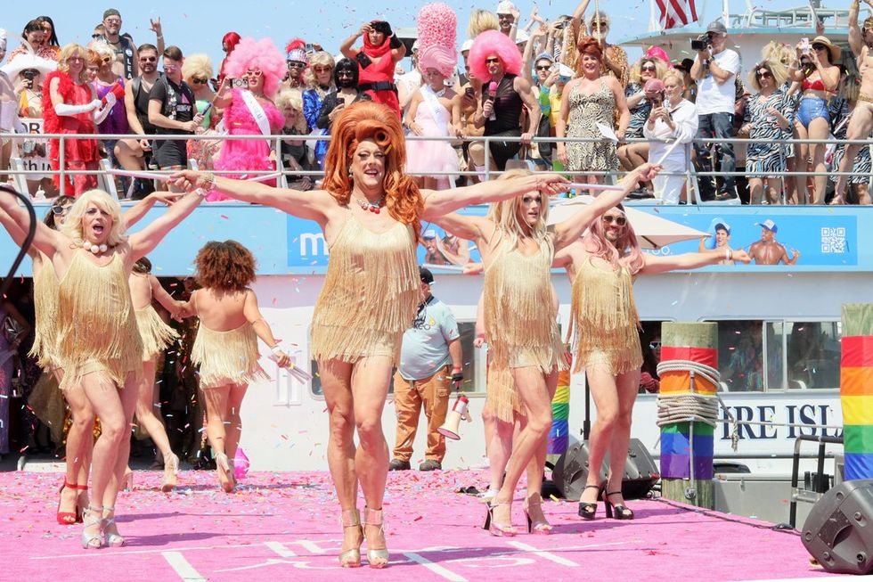 drag queens in gold fringe dresses dance in unison on the stage