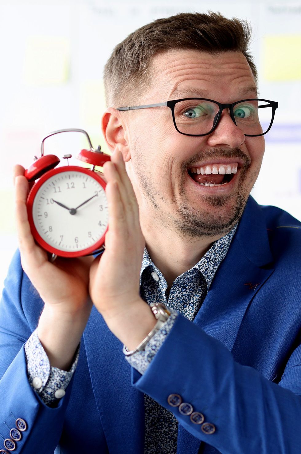 excited business man holding red alarm clock