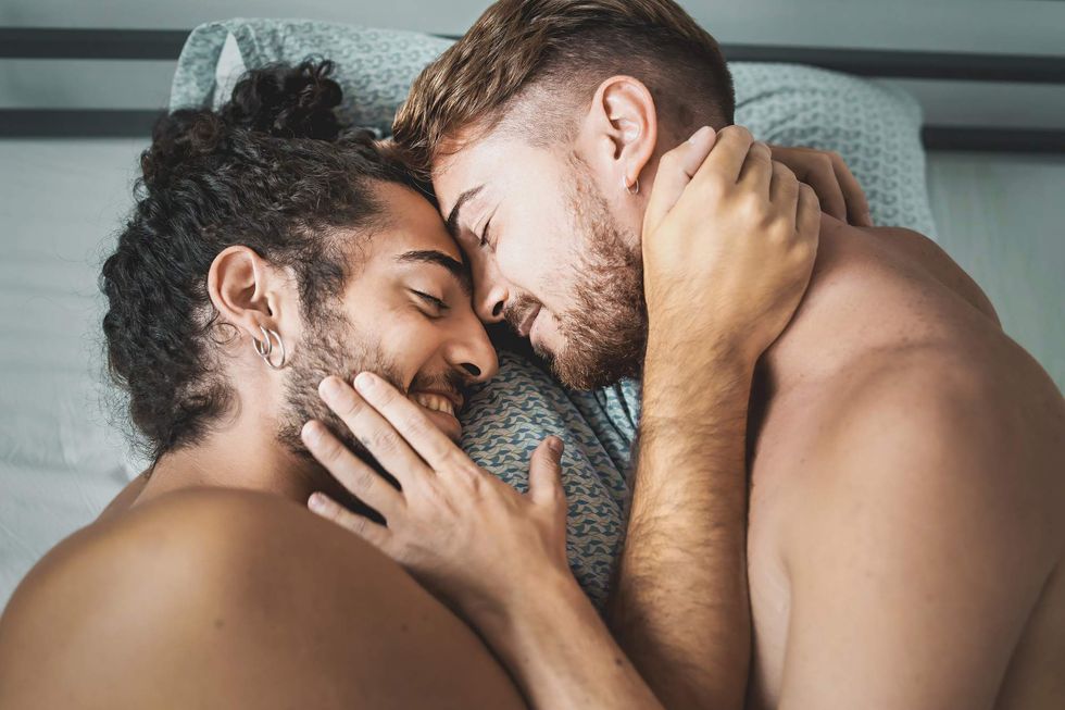 Gay couple lying in bed holding each other