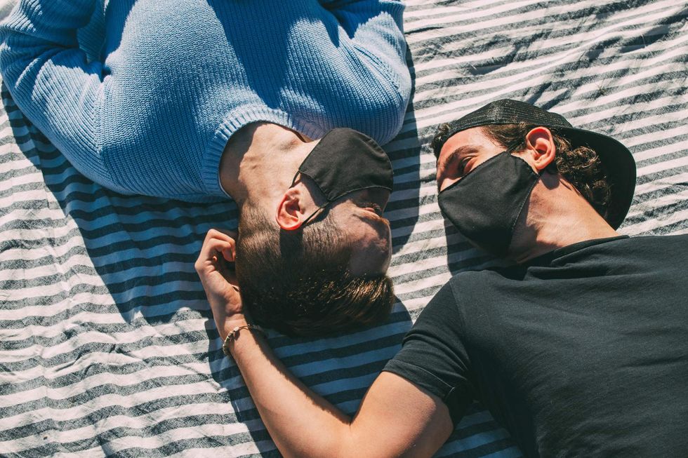 Gay couple lying on a blanket wearing medical masks
