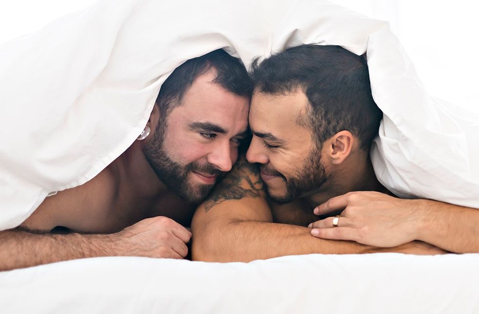 gay men couple smiling with duvet across their head