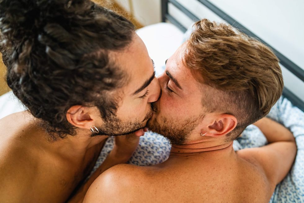 Gay men kissing in bed